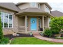 Charming front entrance with a decorative blue door and well-manicured landscaping at 11780 Pebblepointe Pass, Carmel, IN 46033