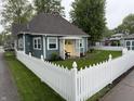 Landscaped front yard featuring a white picket fence and a charming covered porch with seating at 1567 Logan St, Noblesville, IN 46060