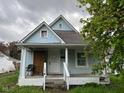 Charming, light blue home features a covered porch, classic columns and well-lit windows with a gabled roof at 1617 E Kelly St, Indianapolis, IN 46203