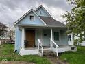 Charming, light blue home features a covered porch, classic columns and well-lit windows with a gabled roof at 1617 E Kelly St, Indianapolis, IN 46203