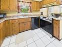 Well-lit kitchen featuring wood cabinetry, stainless steel appliances, white tile flooring, and updated fixtures at 1645 Woodview Ln, Anderson, IN 46011