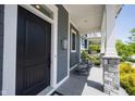 Close up on cozy covered front porch featuring stone pillars, rocking chairs, and a classic black front door at 1648 Rossmay Dr, Westfield, IN 46074