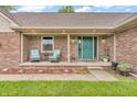 Cozy covered porch with brickwork, seating, and a welcoming teal front door at 1934 Constitution St, Greenfield, IN 46140