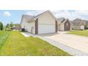 View of house showcasing the attached two-car garage, gravel accents, and well-manicured lawn at 2761 Winding Creek Ln, Greenfield, IN 46140