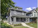 Charming two-story home with gray siding, white trim, a welcoming front porch, and well-manicured landscaping at 2940 N Park Ave, Indianapolis, IN 46205