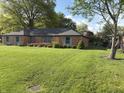 Beautifully landscaped lawn with mature trees surrounding a well maintained brick home at 3128 W 12Th St, Anderson, IN 46011