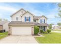 Charming two-story house boasts a two-car garage, manicured lawn, and classic architectural design with blue accents at 5849 Wooden Branch Dr, Indianapolis, IN 46221