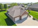 Birds eye view of a brick home with an attached three car garage, driveway and manicured lawn at 6077 W David Wayne Dr, New Palestine, IN 46163