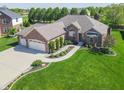 Aerial view of a well-maintained brick home with an attached three car garage and lush, green lawn at 6077 W David Wayne Dr, New Palestine, IN 46163