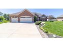 Lovely brick home boasting a three-car garage, concrete driveway, and a meticulously landscaped front yard at 6077 W David Wayne Dr, New Palestine, IN 46163