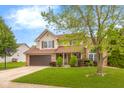 Inviting two-story home showcasing manicured lawn and lovely landscaping with a two car garage at 6096 E Conestoga Trl, Columbus, IN 47203