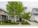 Charming two-story home featuring a covered front porch, attached garage, and well-manicured lawn at 7218 Antiquity Dr, Carmel, IN 46033