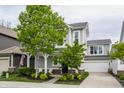 Charming two-story home featuring a covered front porch, attached garage, and well-manicured lawn at 7218 Antiquity Dr, Carmel, IN 46033