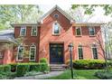 Stately brick home featuring a gabled entryway, arched windows, and manicured shrubbery at 7626 Timber Springs S Dr, Fishers, IN 46038