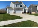 Inviting two-story home featuring a three-car garage, appealing landscaping, and sidewalk at 9074 Larson Dr, Pendleton, IN 46064
