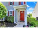 Close-up view of the inviting red front door with a 'Welcome' sign and landscaped surroundings at 9557 W Lantern Ln, Pendleton, IN 46064