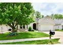 Lovely one-story brick home with an attached garage and mature landscaping and big tree at 10713 Stable Dr, Indianapolis, IN 46239