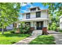 Classic two-story house featuring a brick foundation, covered porch, and lush green lawn at 1124 E 35Th St, Indianapolis, IN 46205