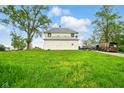 Rear view of farmhouse-style house, surrounded by a grassy field and various vehicles at 1170 E 400 S, Lebanon, IN 46052