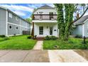 Inviting two-story home with a charming balcony, green lawn, and sidewalk at 1434 Laurel St, Indianapolis, IN 46203