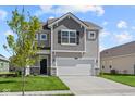 Two-story home featuring a two-car garage, stone accents and gray siding at 1874 Victor Higgins Dr, Shelbyville, IN 46176