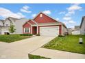 Attractive single-story red home with a two-car garage, green lawn and tidy landscaping at 2006 Monticlair Ln, Columbus, IN 47201