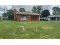 Cozy single-level home with a brick chimney, a well-maintained lawn and an attached garage at 211 Woodlane Dr, Columbus, IN 47201