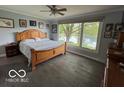 Relaxing bedroom featuring a wooden bed frame, large window with scenic views and hardwood floors at 3829 Waycross Dr, Columbus, IN 47203