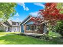 Charming blue home with a cozy front porch framed by a beautiful red tree and a lush green lawn at 5015 Carrollton Ave, Indianapolis, IN 46205