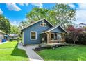 Inviting blue house boasts a well-kept lawn and a charming front porch, creating an appealing first impression at 5015 Carrollton Ave, Indianapolis, IN 46205