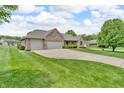 Brick home featuring a two-car garage, manicured lawn, and a mature tree in the front yard at 802 Echo Trl, Martinsville, IN 46151