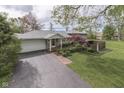 A charming home exterior features manicured landscaping and a long driveway leading to an attached garage at 8903 Maple Hill Dr, Indianapolis, IN 46239