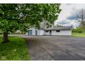 A large detached garage featuring a gray door, adjacent to a spacious asphalt parking area and a smaller garage at 8944 W 21St St, Indianapolis, IN 46234