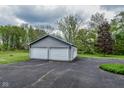 A two-car detached garage with a gray facade and white doors, set on an expansive asphalt driveway at 8944 W 21St St, Indianapolis, IN 46234