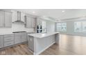 Modern kitchen featuring gray cabinets, a large island, stainless steel appliances, and hardwood floors at 13324 Roundtop Rd, Noblesville, IN 46060