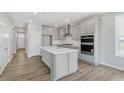 Well-designed kitchen with gray cabinets, a spacious island, stainless steel appliances, and elegant hardwood flooring at 13324 Roundtop Rd, Noblesville, IN 46060