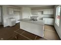 A kitchen is shown with white cabinets, gray countertops, and a spacious island with a stainless steel sink at 1428 Aster Dr, Shelbyville, IN 46176