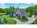 Beautifully landscaped home with a pond, circular driveway, and a detached garage or shed at 1933 S 825 E, Zionsville, IN 46077