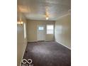 View of the living room with neutral walls and carpet, plus a white front door and window at 2202 E Brookside Ave, Indianapolis, IN 46218