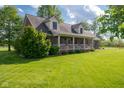 Beautiful brick home with a welcoming front porch, decorative bunting, and lush green lawn, perfect for outdoor enjoyment at 2221 W County Road 500 N, Danville, IN 46122