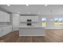 Bright kitchen with an island, white cabinets, modern appliances, and wood flooring at 4076 Berry Chase Blvd, Greenwood, IN 46143