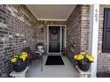 Covered front porch with seating, potted plants, and a decorative wreath on the front door at 509 Tulip Tree Dr, Lapel, IN 46051