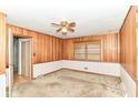 Bedroom with wood paneling, carpet, window with blinds and ceiling fan at 5101 Dickson Rd, Indianapolis, IN 46226