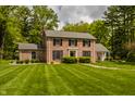Elegant brick home with black shutters, surrounded by a well-maintained lawn and mature trees at 5800 Lawrence Dr, Indianapolis, IN 46226
