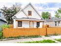 Charming two-story home with a bright yellow fence and mature shade trees at 647 Coffey St, Indianapolis, IN 46221