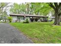 Charming single-story home with well-manicured lawn, mature trees, long driveway, and an American flag at 7228 Kimberly Ln, Plainfield, IN 46168