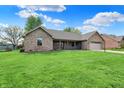 Inviting one-story brick home showcasing a lush green lawn and a covered front porch at 815 Stewart Rd, Anderson, IN 46012