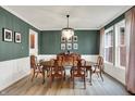 Elegant dining room featuring hardwood floors, stylish lighting, and beautiful dark green wall color at 9179 Brookstone Pl, Zionsville, IN 46077
