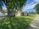 Quaint single-story home with a lush green lawn, mature trees, and charming curb appeal at 1122 Shelby St, Shelbyville, IN 46176