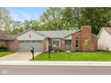 Charming single-story home with a brick chimney, gray siding, well-maintained lawn, and an attached two-car garage at 12290 Charing Cross Rd, Carmel, IN 46033